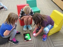 Three girls playing on an iPad at Learning Commons