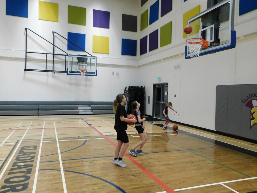 Girls practicing basketball shoots at gym